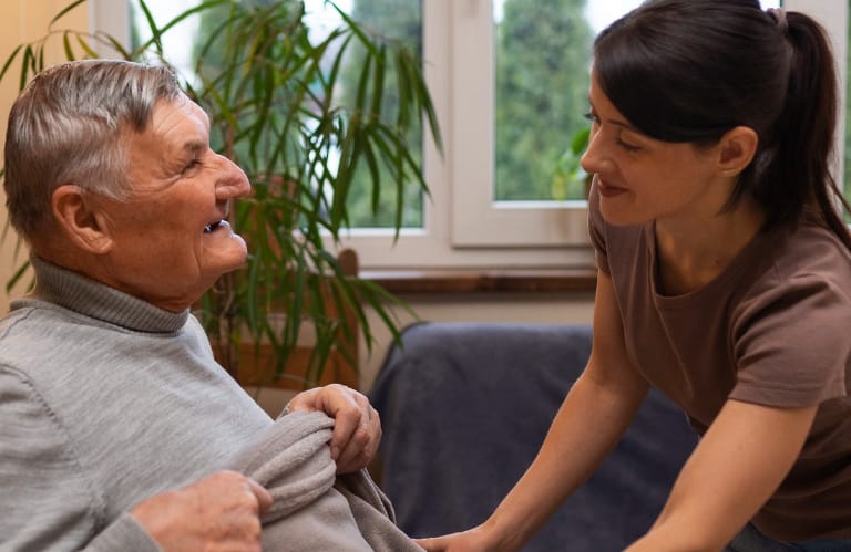 Caretaker helping put a blanket on an older man